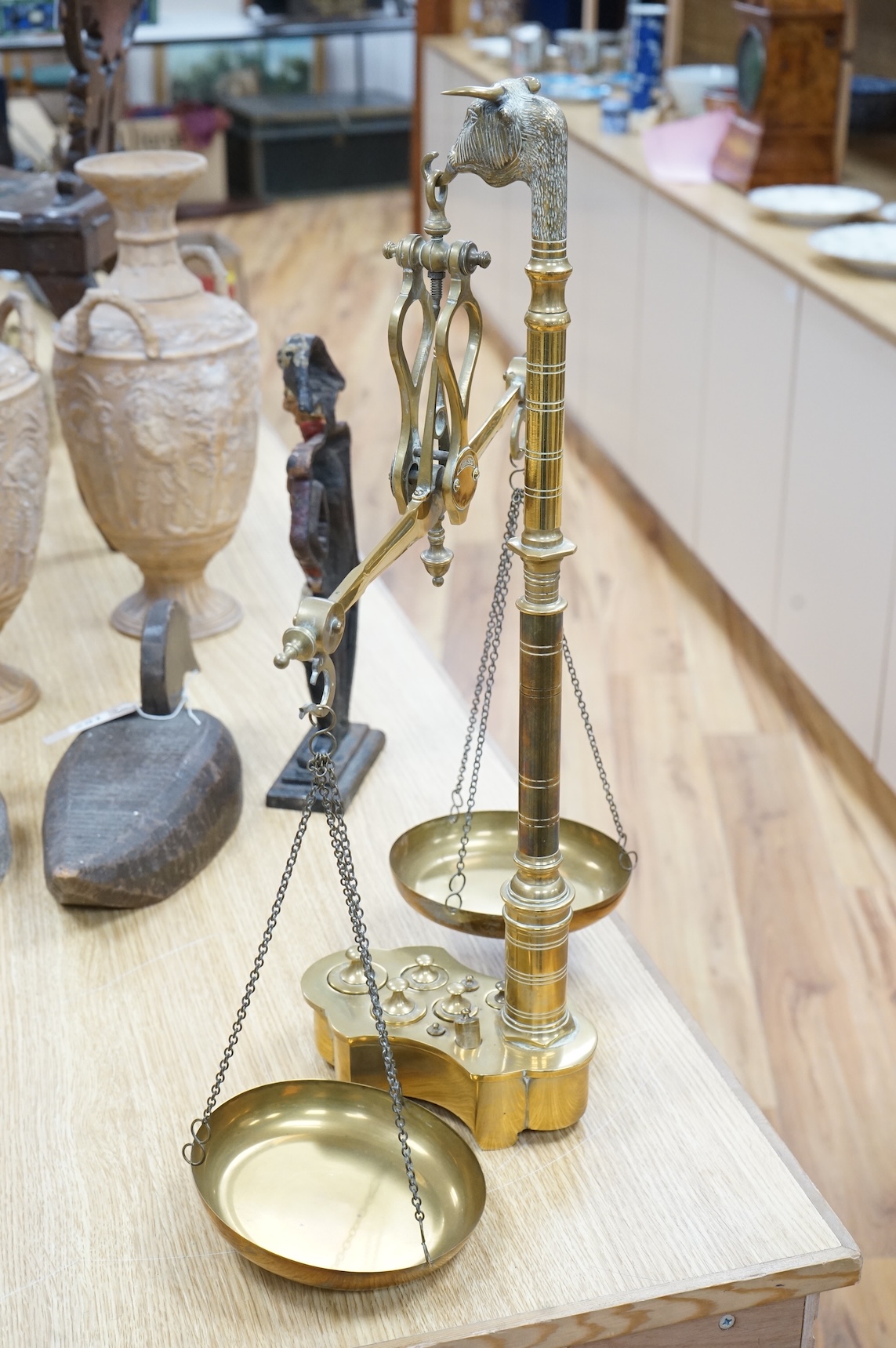A pair of brass beam scales with decorative bull's head finial and weights, 56cm high